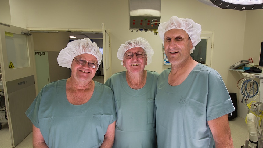 Three men in hospital gowns inside a surgery