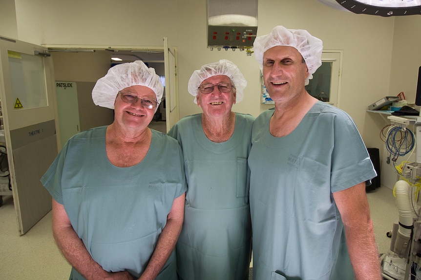 Three men in hospital gowns inside a surgery