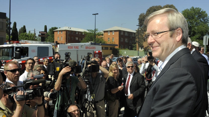 Kevin Rudd, wearing a big grin, surrounded by media. File photo.