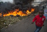 Child runs past burning tires in South Africa