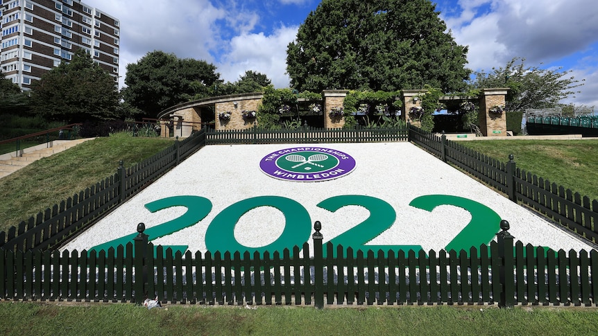A view of a display that says 2022 under the wimbledon logo inside a fence