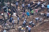 Rescuers are seen amid debris digging into the ground as they search for victims after a landslide.