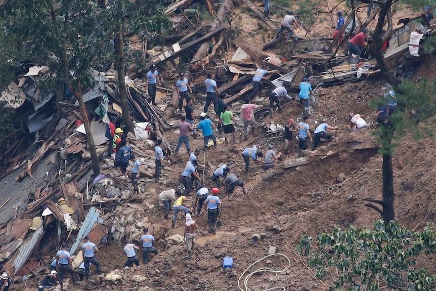 Rescuers are seen amid debris digging into the ground as they search for victims after a landslide.