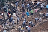 Rescuers are seen amid debris digging into the ground as they search for victims after a landslide.