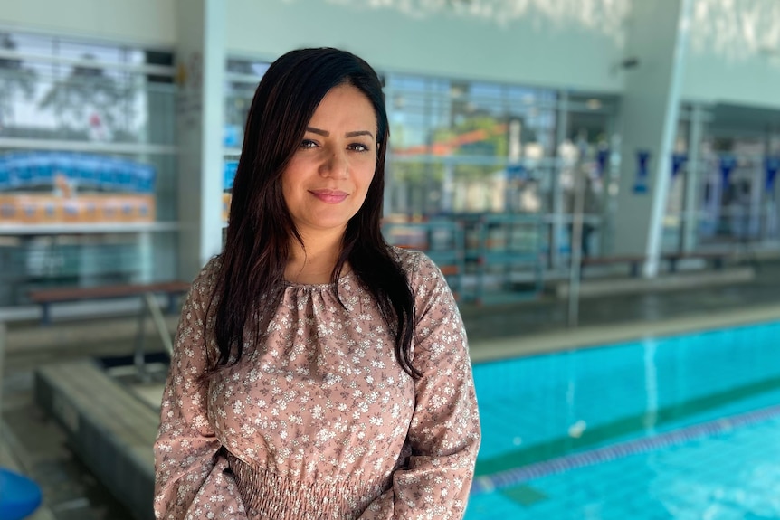 A woman stands in front of a swimming pool