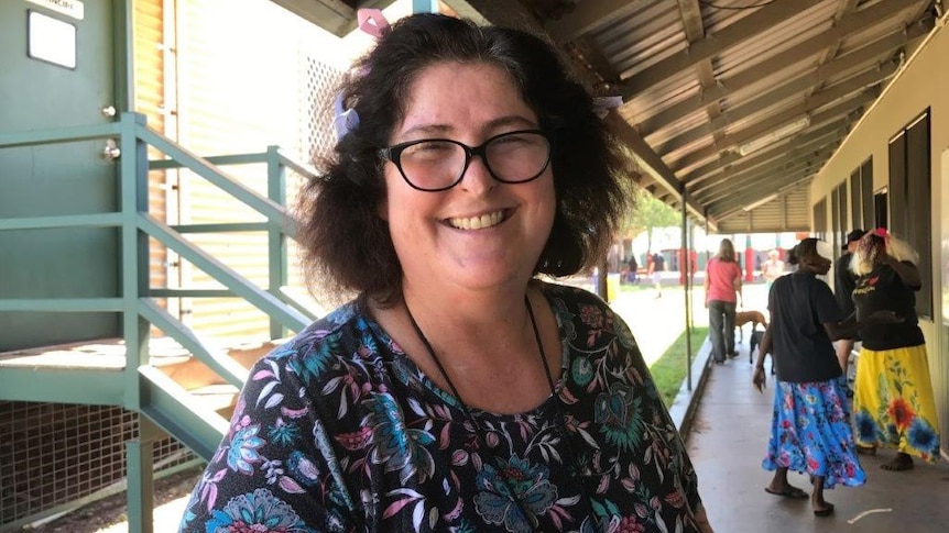 Woman smiling on school verandah people in background.