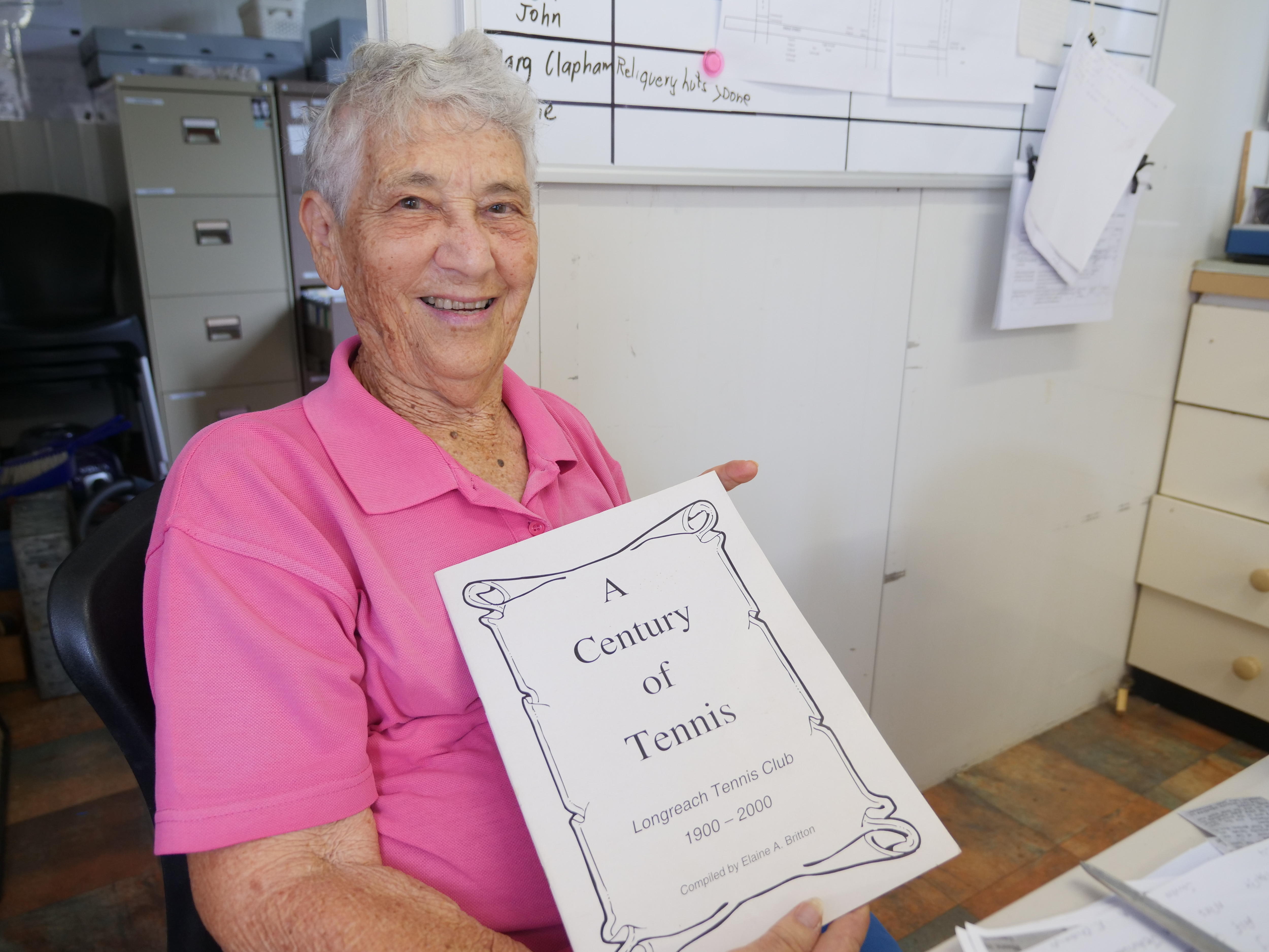 Old woman in pink shirt holding a book