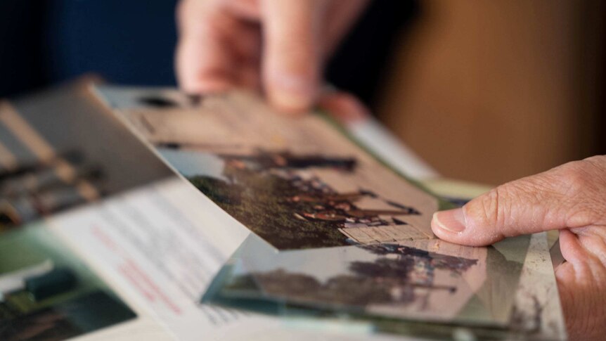 A close up photo of a person looking through old printed photos.