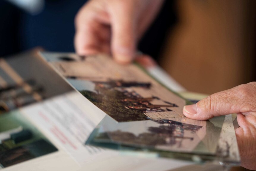 A close up photo of a person looking through old printed photos.