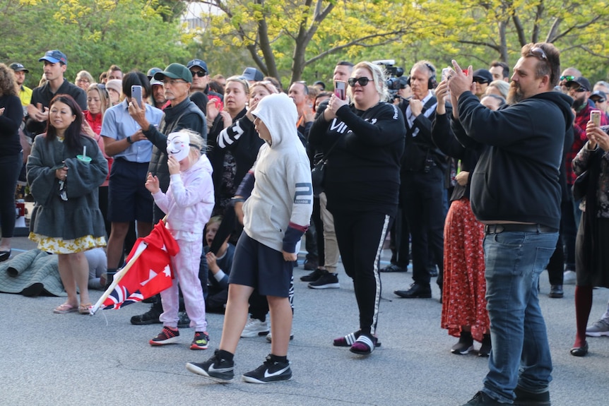 Children and other protesters gather outside Dumas House in Perth