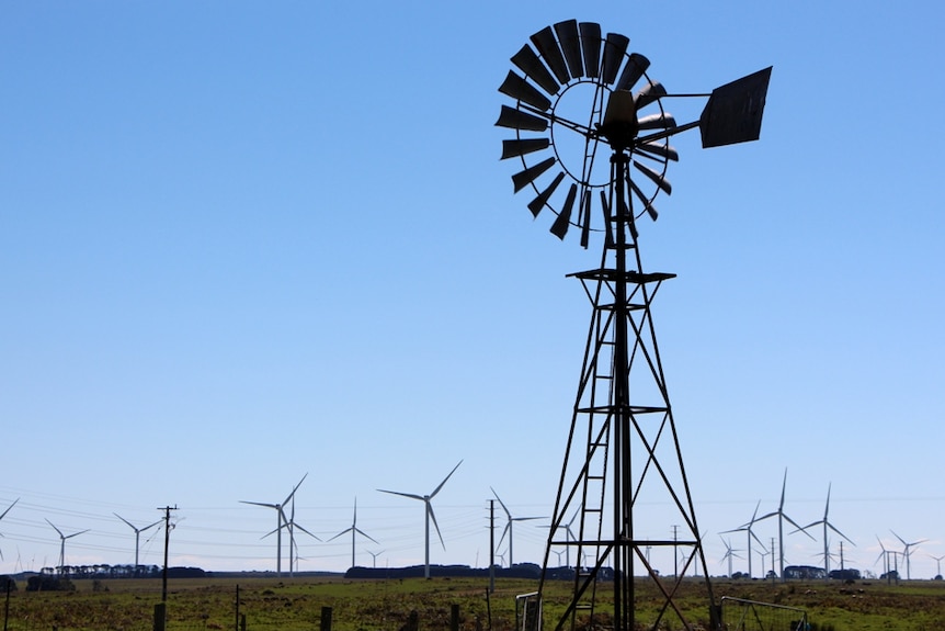 Eine Windmühle steht mit Windkraftanlagen im Hintergrund