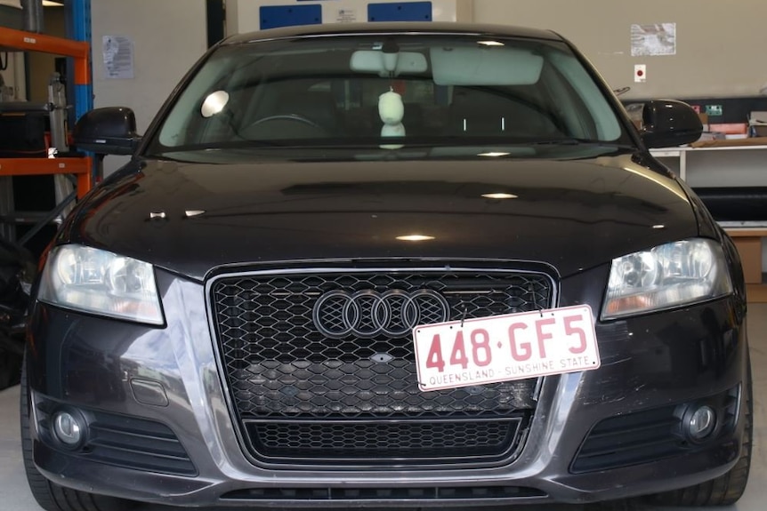 A black audi with its liscense plate ziptied on,