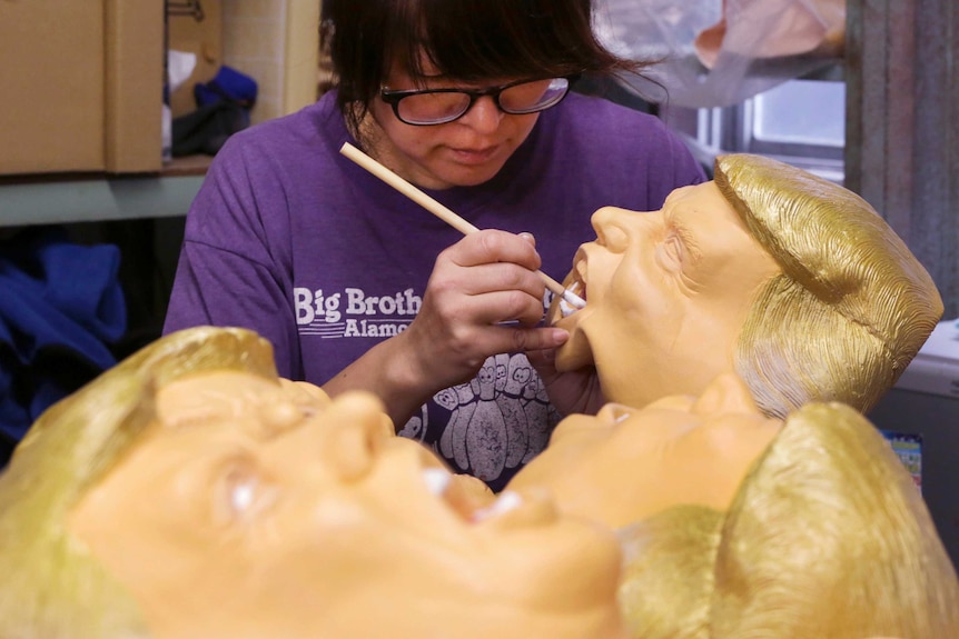 A worker paints a rubber mask depicting Donald Trump.