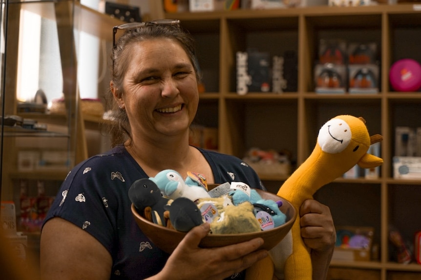 Woman holding sensory toys including a giraffe inside a store. 