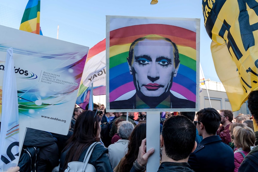 Protester holds a 'gay clown' poster of Russian President Vladimir Putin