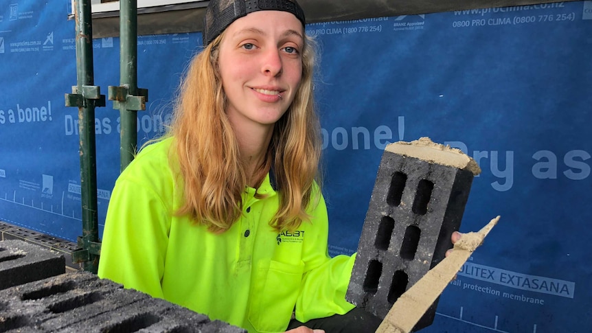 Chelsea Whelan, a bricklaying apprentice, poses with a brick and some