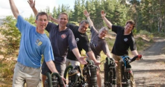 Group of men with arm in air and dive tanks