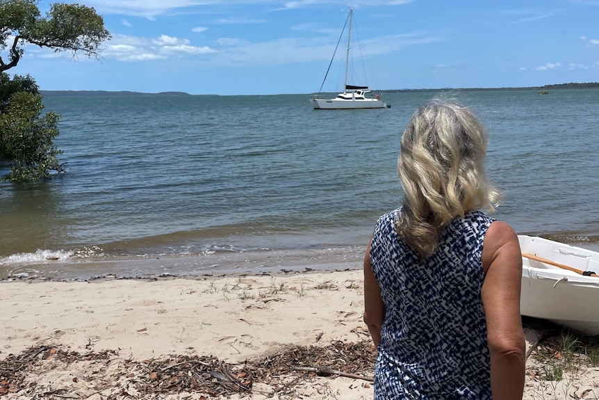 The back of a woman's head as she looks out over the water to a boat