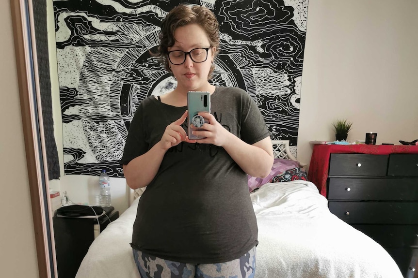 A woman in exercise clothes takes a selfie in the mirror of a bedroom. For story on women finding exercise that suits them.