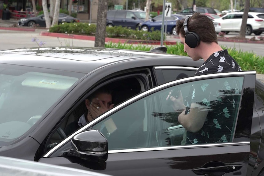 A woman being interviewed wipes a tear from her eye.