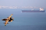 A file photo of an Iranian military fighter plane flying past an oil tanker during naval manoeuvres in the Gulf and Sea of Oman