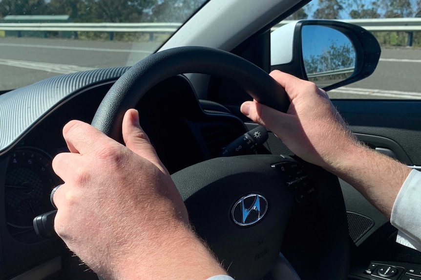 Closeup of a man's hands on the steering wheel of a car.