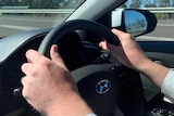 Closeup of a man's hands on the steering wheel of a car.