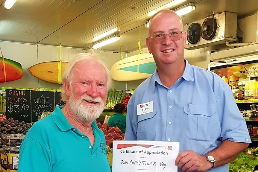 Two men stand shaking hands, holding a certificate.