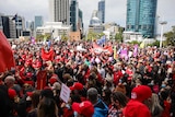 A large gathering of people protesting outside parliament house. 