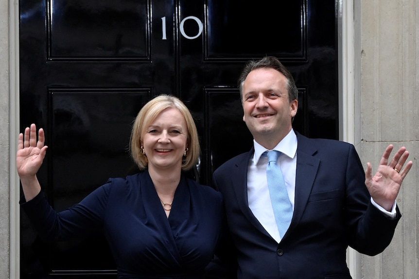 Liz Truss and her husband Hugh O'Leary smile and wave as they stand outside 10 Downing Street.