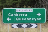 A roadside sign showing Queanbeyan is 4 kilometres in one direction and Canberra is 13 kilometres the other way.