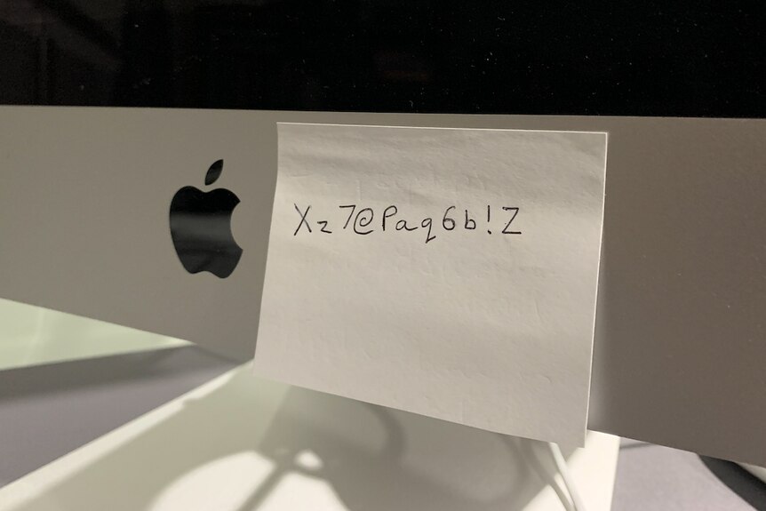 A post-it note stuck on a computer with a password written on it.