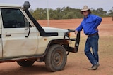 Far West grazier Lachlan Gall leaning on a ute in outback NSW.