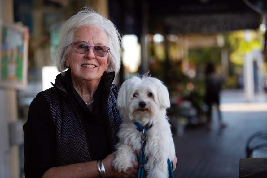 A lady holding a fluffy white dog.