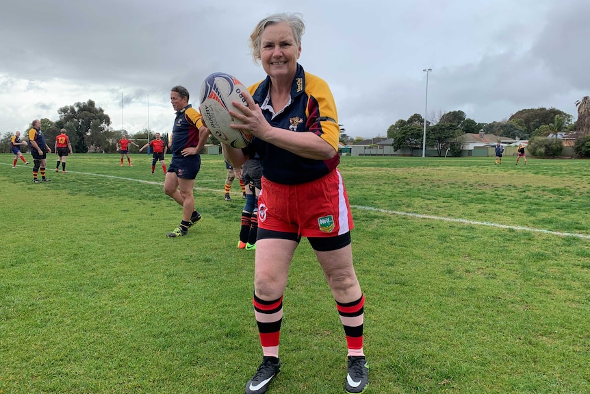A senior female rugby player holds the ball