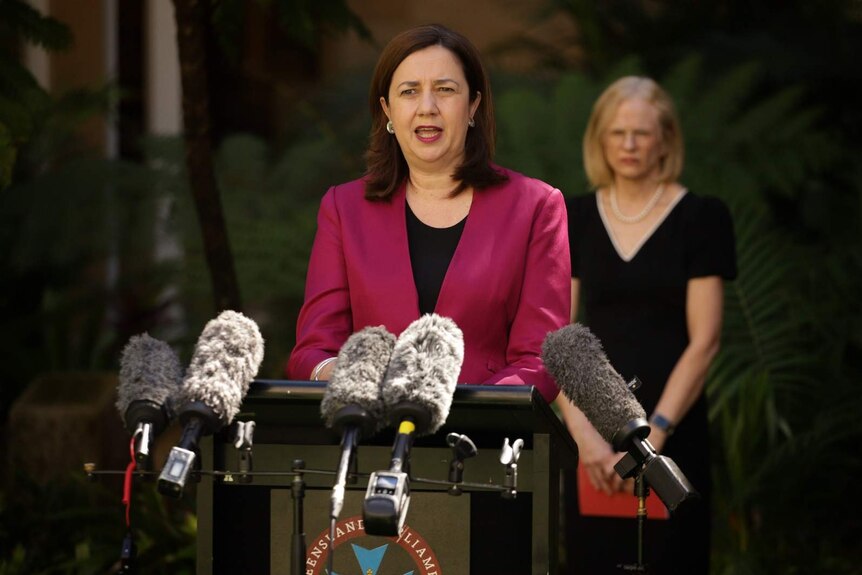 Premier Annastacia Palaszczuk speaking in front of a row of microphones outside State Parliament