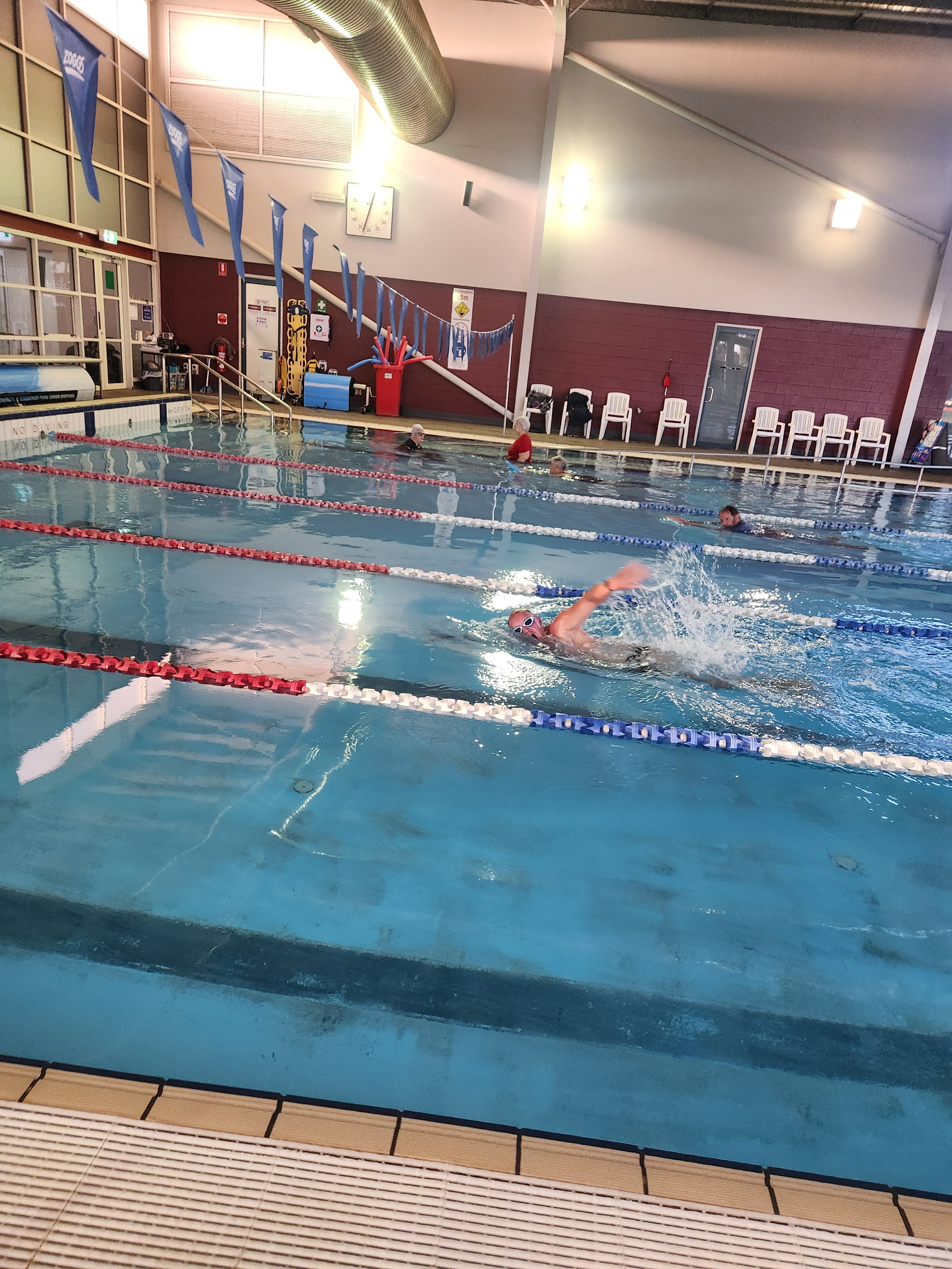A man swimming laps at an indoor swimming pool