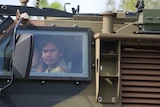 Two Indigenous teens ride in an army tank