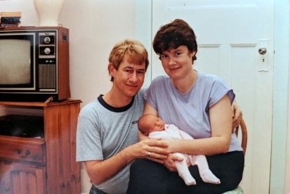 An old photograph of a father with a mother holding her sleeping newborn baby.