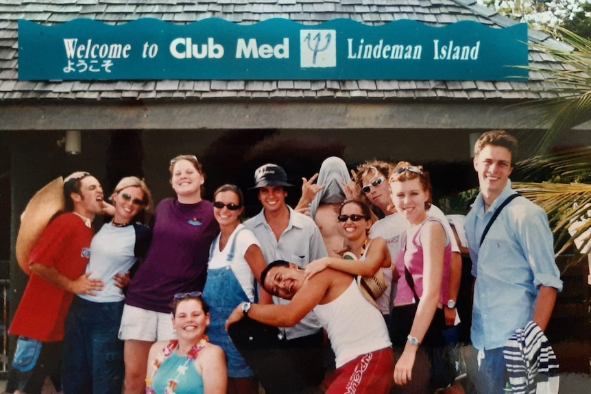 A group of young workers pictured in the early 2000s infront of a sign on Lindeman Island. 