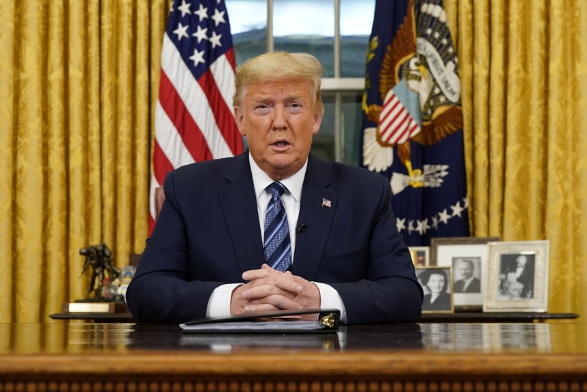 Donald Trump looks directly at the camera while sitting at his Oval Office desk