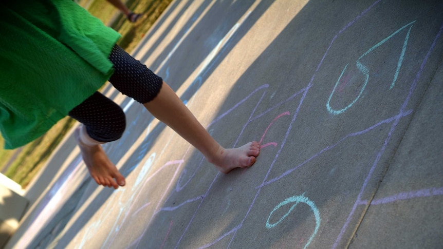 The feet of a child playing hopscotch
