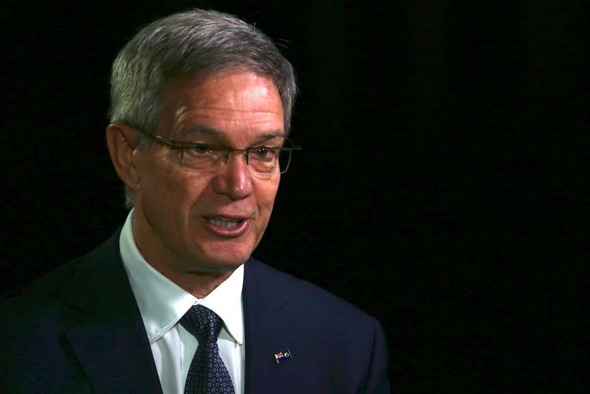 Headshot of Mike Nahan being interviewed under bright light in a dark studio.