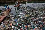 people on a rafe in a canal polluted with plastic