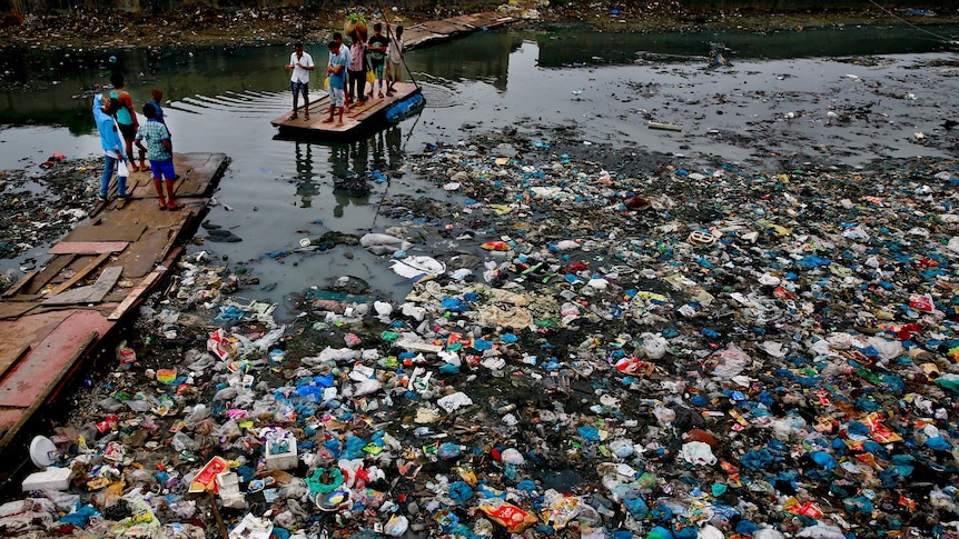 people on a rafe in a canal polluted with plastic