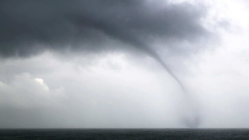 A water spout forms off the coast.