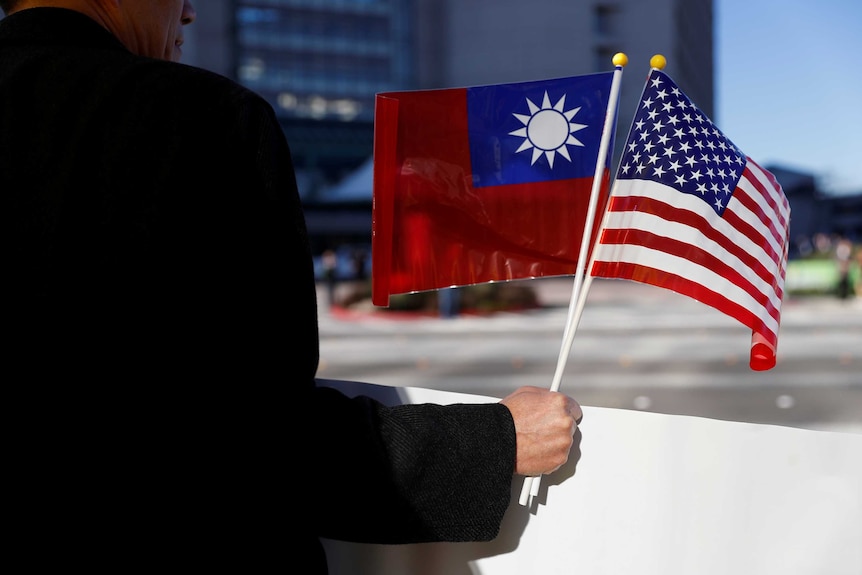一名男性拿着台湾和美国的国旗