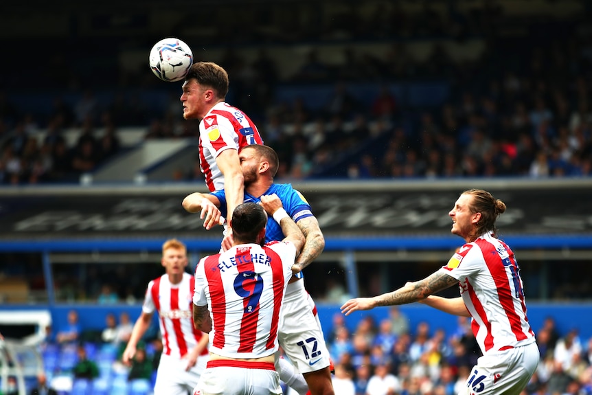Harry Souttar heads the ball, jumping above four other players