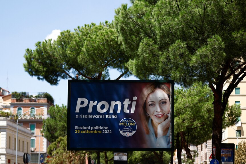 A poster of a middle-aged blonde woman with election-related text, on an Italian street