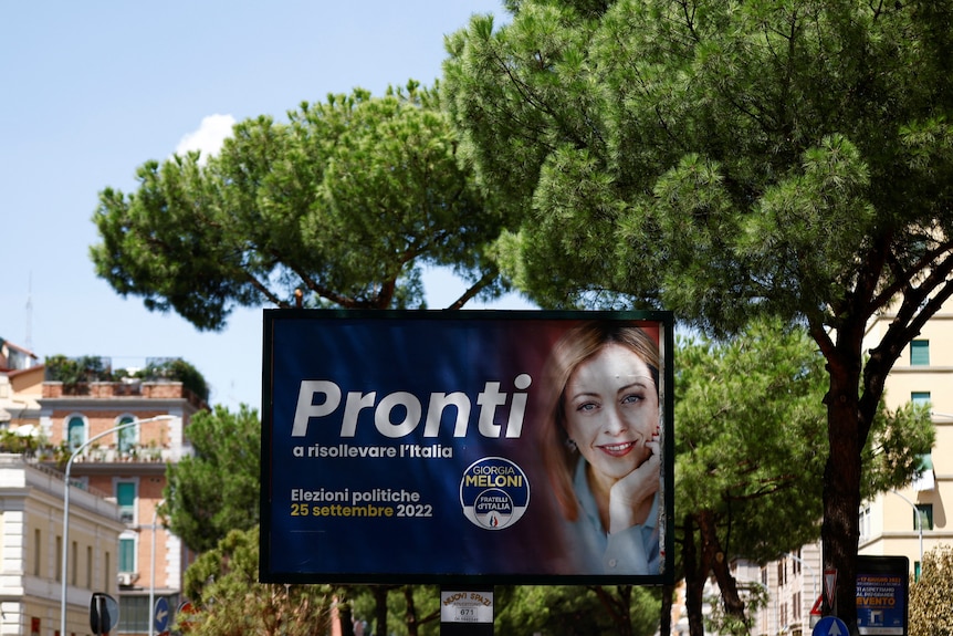 A poster of a middle-aged blonde woman with election-related text, on an Italian street